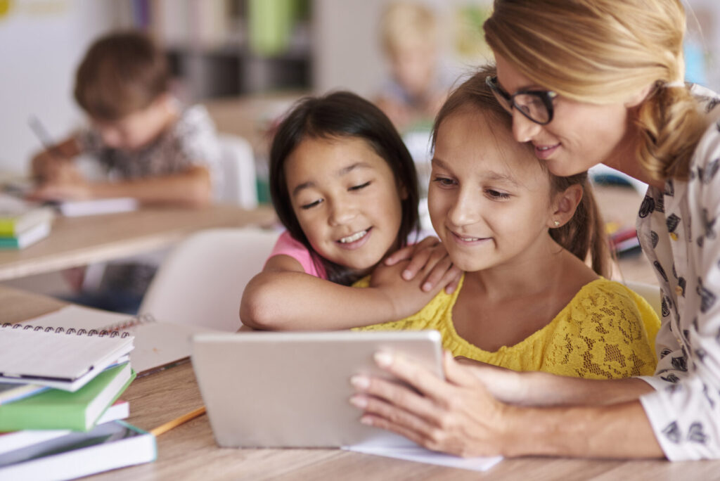 Lærer hjælper elever med digital tablet