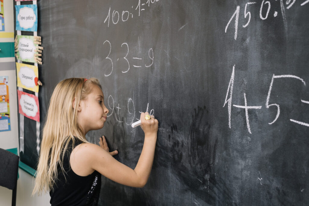 Pige står ved en kridttavle og løser matematiske opgaver